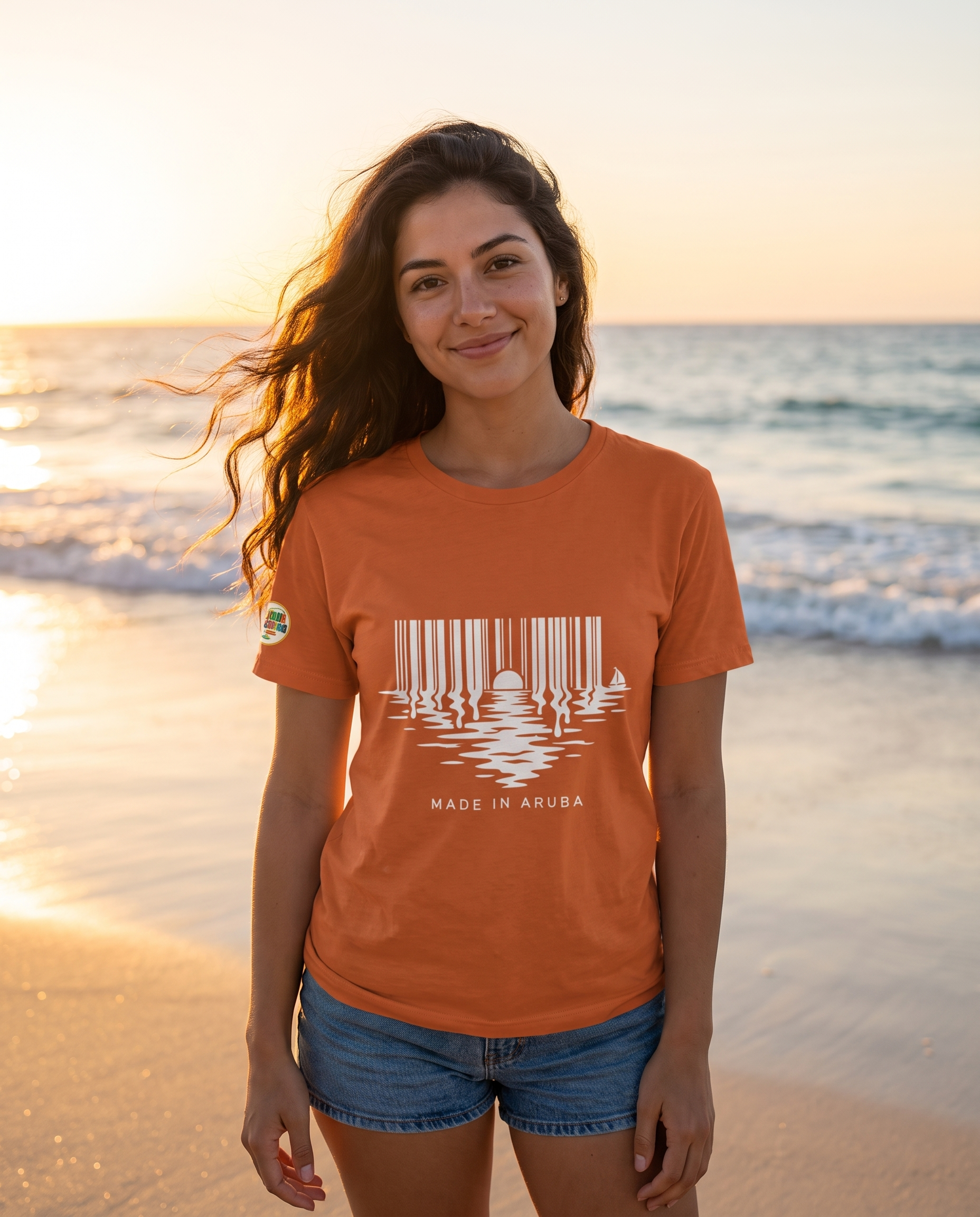 Made in Aruba Barcode Sunset Tee in Burnt Orange, worn at golden hour on Eagle Beach, Aruba
