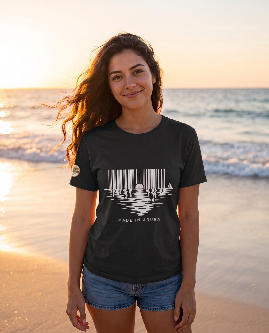 Made in Aruba Barcode Sunset Tee in Black, worn at golden hour on Eagle Beach, Aruba